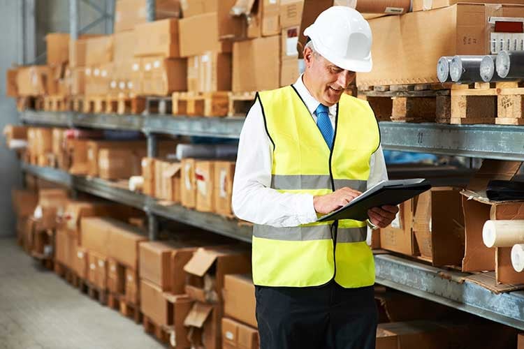 An employee digitally taking stock on an ipad in a warehouse.