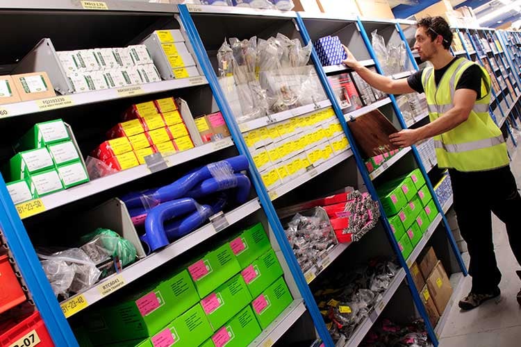 An employee in a shop, restocking auto parts and tools.