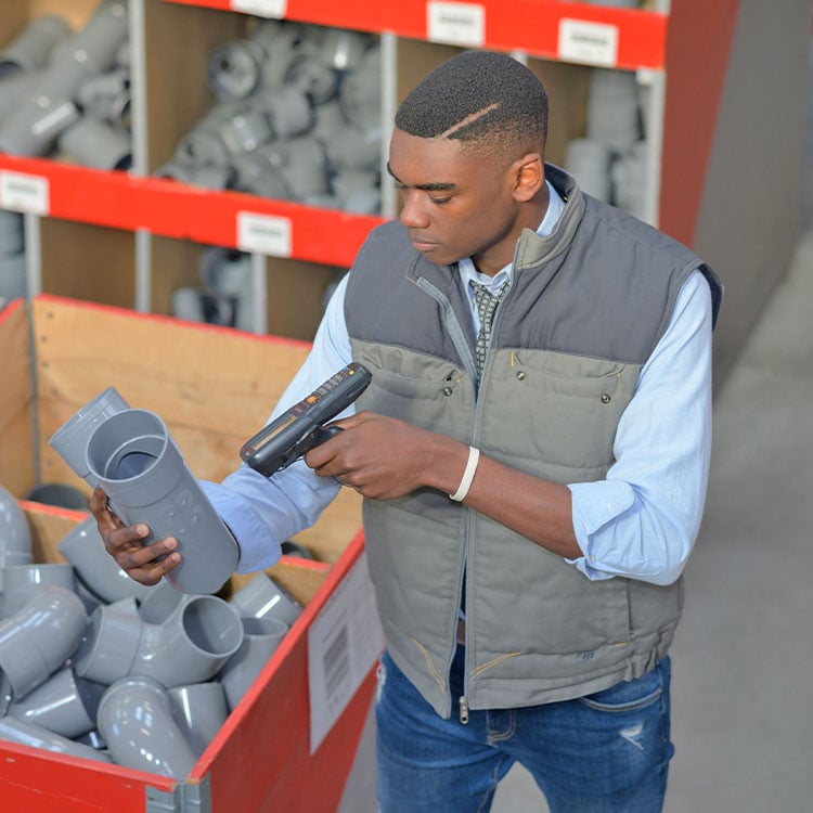 An employee in a plumbing store scanning stock and looking up pricing.