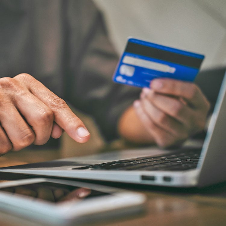 A businessman holding credit card and typing on laptop