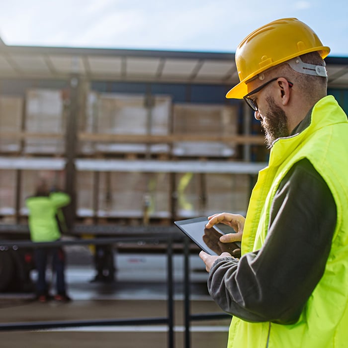 A warehouse worker looking at an ipad while making a delivery