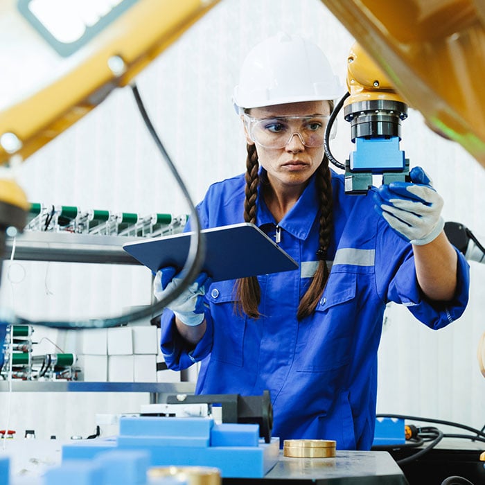 A female employee working in a warehouse inspecting machinery 