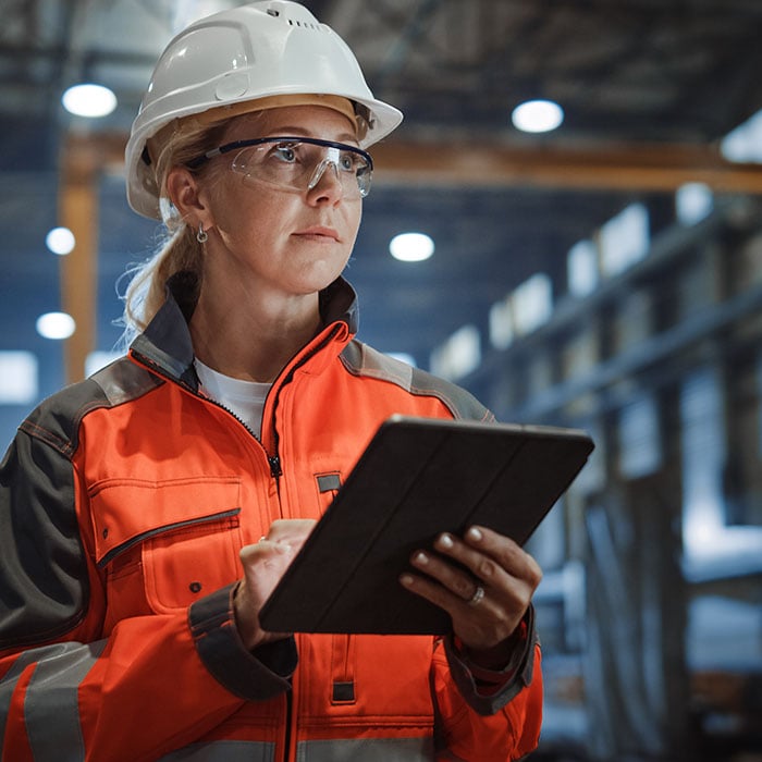 A female employee in a warehouse working on an ipad.