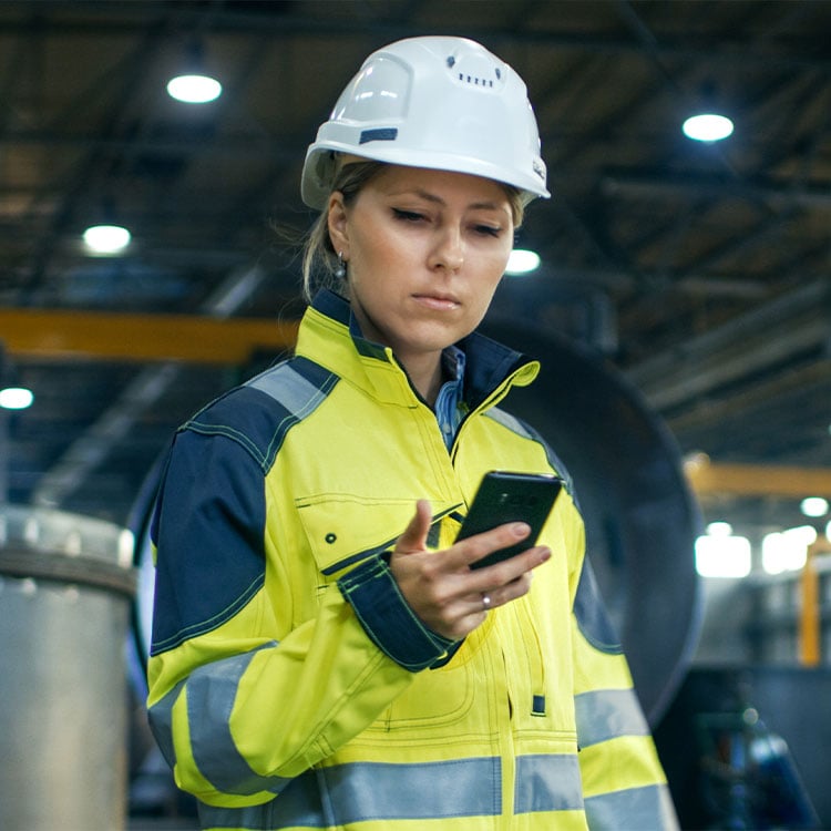 An employee in a warehouse looking at a cellphone.