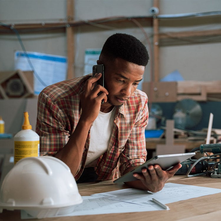 A handyman looking at his phone while on site.